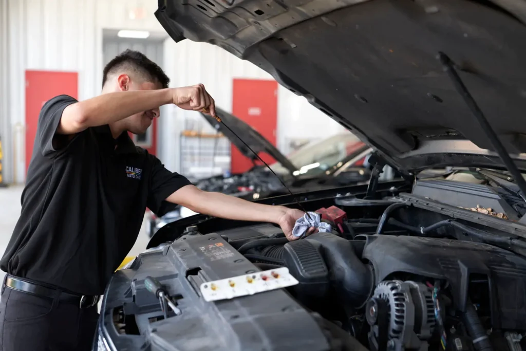 Auto mechanic checking oil